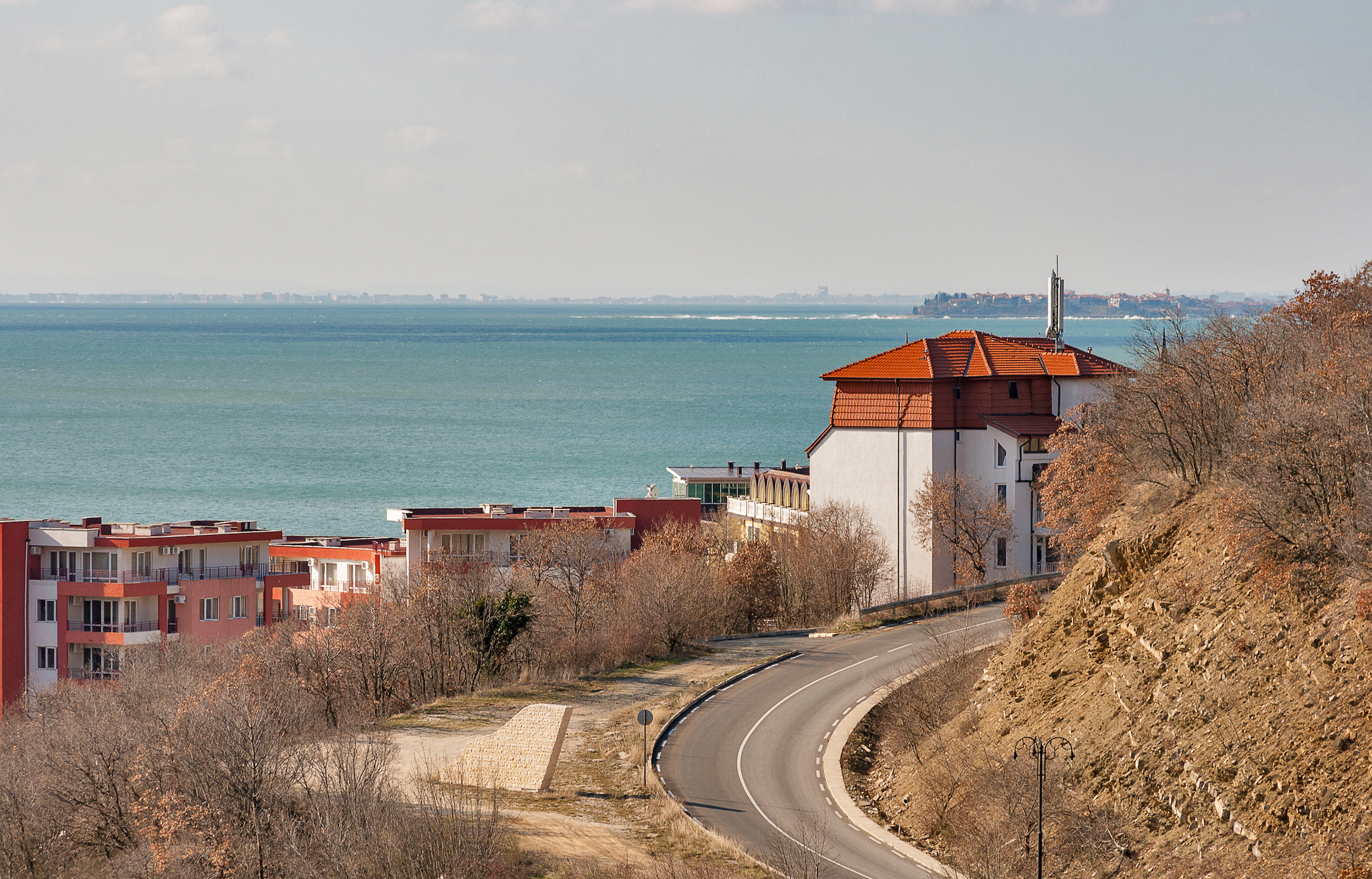 Kręta droga i nowe nowoczesne domki do wynajęcia w czarnomorskim letnim kurorcie turystycznym Elenite, Bułgaria. W tle miasto Nesebar.