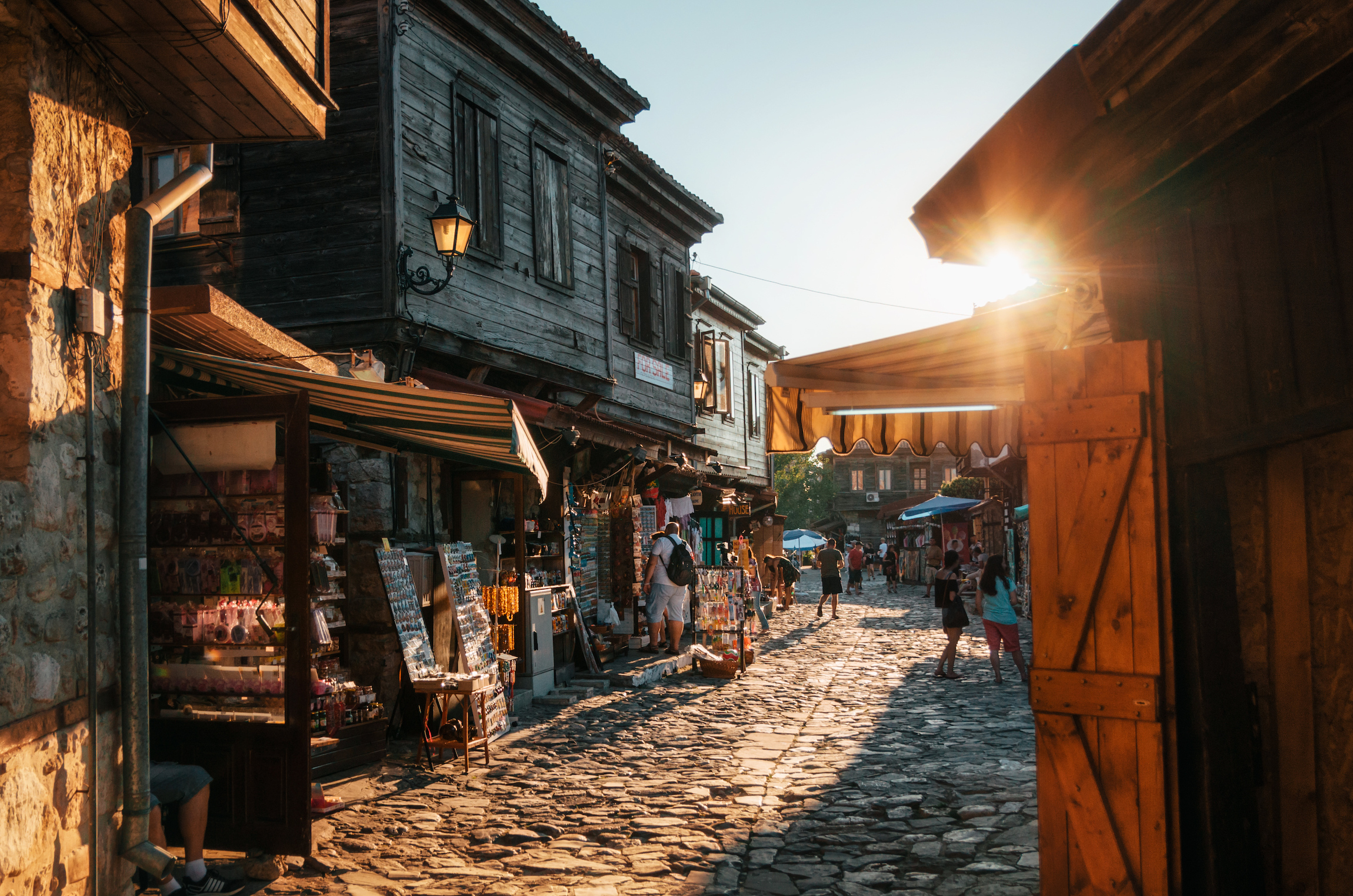 Ludzie spacerują po pieszych brukowanych uliczkach starożytnego Nessebaru z kawiarniami, restauracjami i sklepami z pamiątkami o zachodzie słońca.