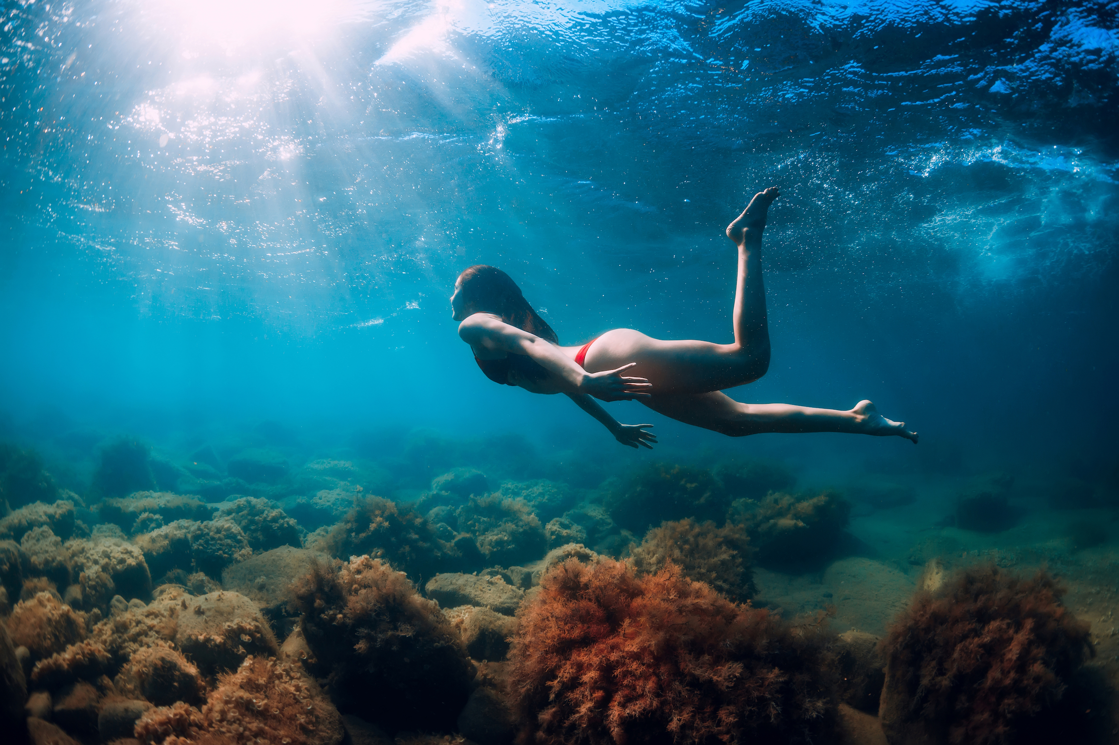 Młoda kobieta pływać i nurkować pod wodą w niebieskim morzu. Aktywność letnie dni na morzu