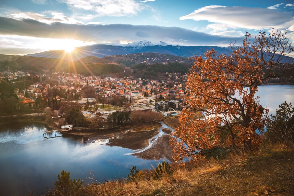 Beautiful sunset over a lake with autumn trees and town in the backgroud. Pancharevo , Bulgaria