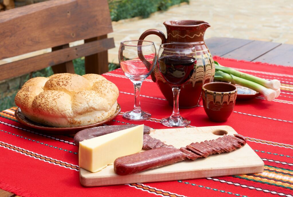 Traditional Bulgarian food wine, saussage and yellow cheese on rural table