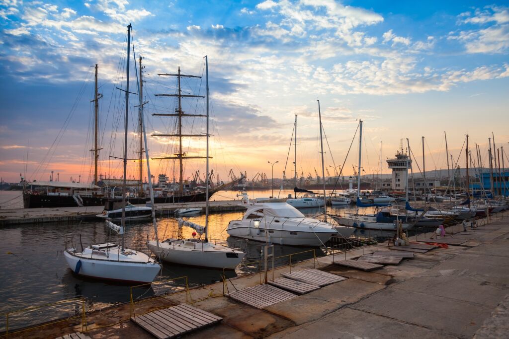 Sailing ships and yachts stand moored in Varna port at the sunset. Black Sea coast, Bulgaria